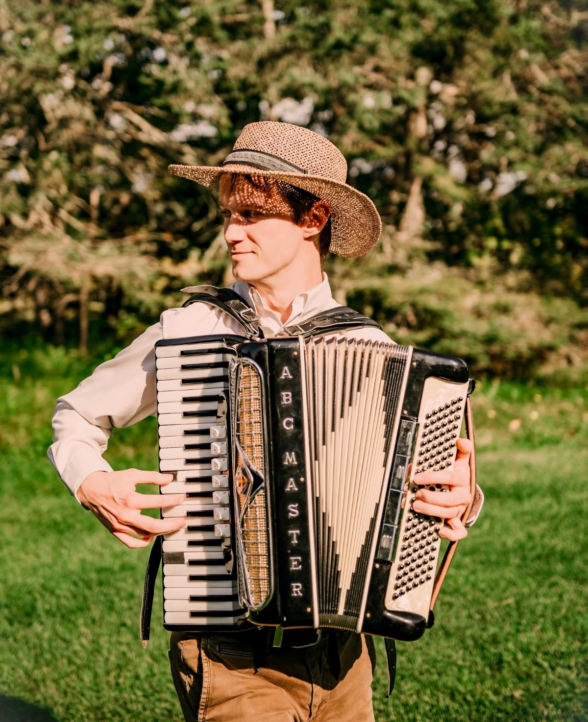 Mark playing accordion outdoors with a sunhat and a smile